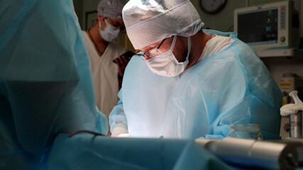 Focused surgeon in blue scrubs performs a delicate operation in a hospital operating room, highlighting precision and teamwork in healthcare