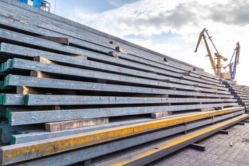 Hot Rolled Steel Square Bar in an open warehouse on the background of a gantry crane