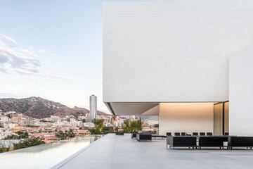 Fototapeta premium Modern architecture overlooking a city with mountains in the background during sunset