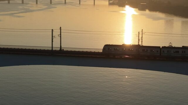 A subway train crossing Dangsan Bridge in Seoul against a backdrop of a reddish-yellow sunrise