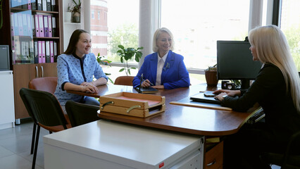 Three professional women seated in office conversing about job responsibilities modern women. Seated in office three businesswomen discuss work collaboration communication professional success.