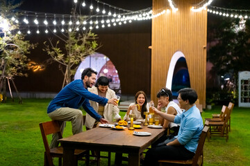 Group of Happy Asian millennials people enjoy and fun celebration reunion meeting holiday event at outdoor dinner party with food and drink together in the garden at restaurant on vacation night.
