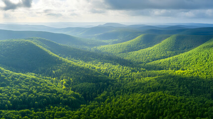 Fototapeta premium Lush green mountain range with sunlight filtering through the clouds.