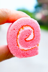 Pink bakery bread, held in hand ready to serve, on blurred background.