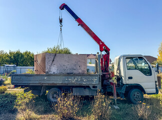 A crane is lifting a large object from a truck © schankz