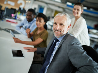 Portrait, mature man and confident in meeting, entrepreneur and publicist with creative company and project. Smile, leadership and person with employees, happy and team in office and public relations