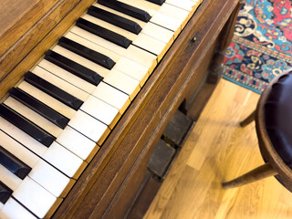 A piano with black and white keys sits on a wooden floor