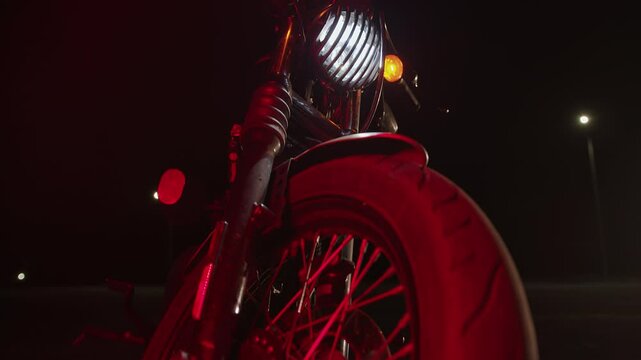 Motorcycle cruiser with headlights on in night parking lot. Slow motion. Front view. Riding motorcycle requires extreme concentration, prudence and quick reaction