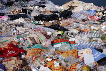 A large pile of mixed waste, including plastic, fabric, and other debris have been thrown in the...
