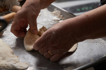 Close-up of an elderly woman's hands preparing cheese-filled panzerotto in a rustic pan, highlighting traditional cooking techniques.