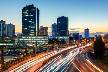 Fototapeta premium Evening traffic flows through downtown with skyline buildings
