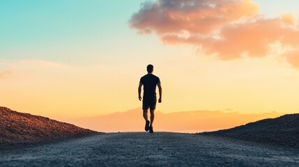 Obraz premium A silhouette of a man walking along a dirt path towards a vibrant sunset, symbolizing solitude and personal journey.