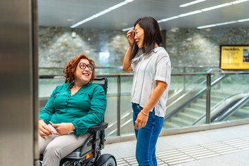 Smiling disabled woman and friend talking waiting for subway elevator