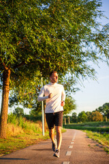 Fototapeta premium Young sportsman running in park wearing earphones and smartwatch