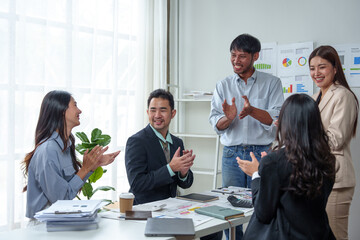Team of cheerful Asian businessmen applauding their colleagues for their work success. Welcoming new employees Business team celebrates success together at work, clapping to congratulate each other.