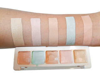 A woman's hand is trying to apply a cosmetic product color corrector or concealer on her hand neatly in a square shape, isolated on white background and close up shot.