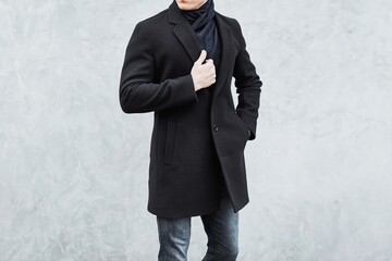 Fashionable man wearing black coat and jeans in urban setting