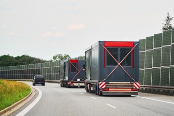 Large trucks carrying modular houses buildings on freeway