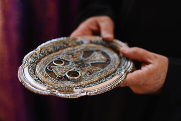 Ornate silver tray with wedding rings in ceremony.