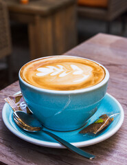 A fresh hot cappuccino in a blue cup with flower on the top