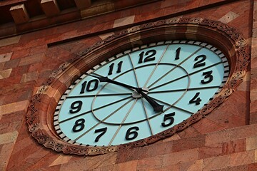 A large clock on the wall of a government building covered with pink tuff in Yerevan