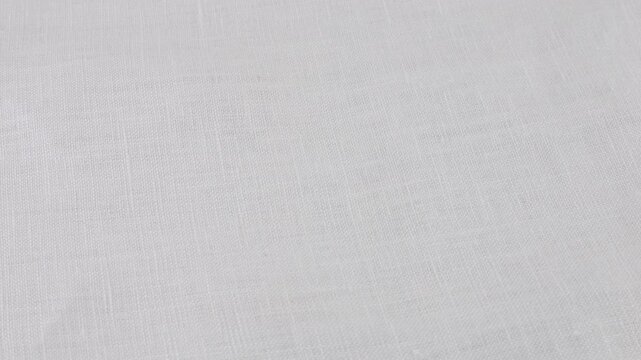 Top view of  white linen fabric rotates on the showcase. Top view of textile background. Theme design, fashion, tailoring of clothes.