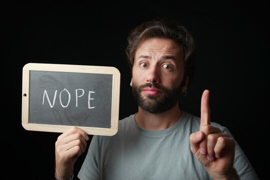 Caucasian Man holding a Chalkboard with the Handwritten word  "Nope"