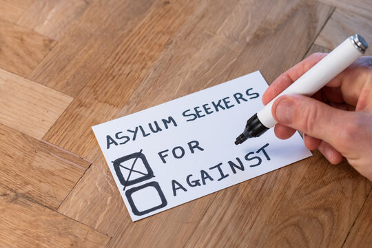 human hand with marker casts support vote on popular trending topic asylum seekers. public opinion varies around immigration, help, aid and shelter to be offered foreign nationals with refugee status
