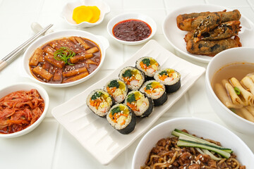 Assortment of Korean traditional dishes. Gimbap, tteokbokki, odeng, danmuji, kimchi, gimmari, jjangmyeon. Flat lay.
