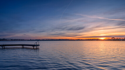 Obraz premium Beautiful sunset over a lake with a jetty