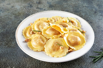 Ravioli pasta filled with pumpkin, nuts and fresh herbs on white background. 