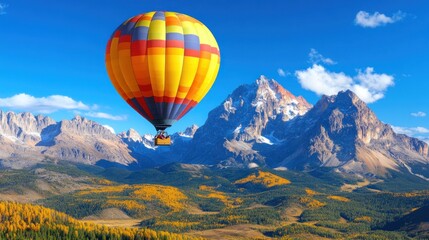 Obraz premium A vibrant hot air balloon floats gracefully over an expansive landscape adorned with golden autumn leaves and towering mountains under a clear blue sky