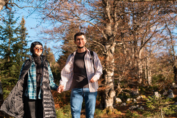 A happy couple traveler walking together with holding hands in the autumn forest during the hike, adventure travel.