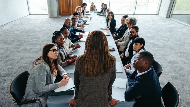 Female leader addressing business team in boardroom meeting