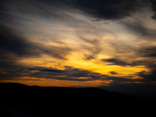 Fototapeta premium A stunning sunset over Schauinsland, with dramatic clouds and warm hues filling the sky. The vibrant colors create a mesmerizing scene as the day fades into night.