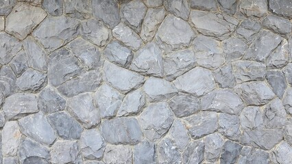 Large grey round stone wall. Stone wall texture background. The surface of a stone structure is composed of multiple stones.