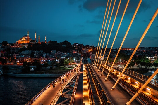 Halic Metro Bridge. In the background, the Halic Metro Bridge and the magnificent Suleymaniye Mosque. View of the Golden Horn at night. Istanbul, Turkey.