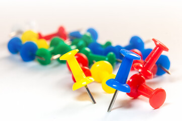 Colorful push pins scattered on white background