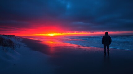 Fototapeta premium Solitary Figure Gazing at a Vibrant Sunset Over the Ocean
