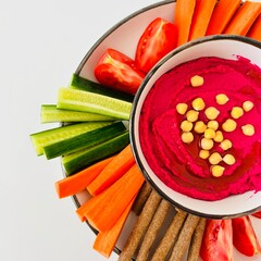 Beet Hummus Dip with Chickpeas on Top and Vegetables on Plate