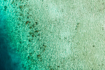 The serene turquoise waters gently lap against a sandy shoreline dotted with coral formations,...