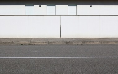 White plaster fence of modern house with closed shutters  behind. Cement sidewalk and asphat road in front. Background for copy space