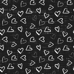 A seamless  pattern of various hand-drawn white hearts tossed on a black background