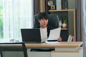 A beautiful businesswoman is sitting and looking at a computer screen, writing a plan, and planning daily appointments.