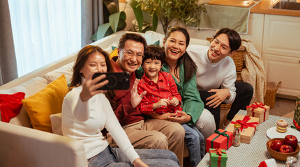 parent, happiness, communication, relaxation, celebrating, happy, enjoyment, relax, smartphone, selfie. A family is sitting on a couch and taking a picture with smartphone. Scene is happy and joyful.