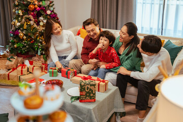 presents, happiness, family, celebrating, enjoying, happy, celebrate, present, celebration, christmas. A family is gathered around a Christmas tree.