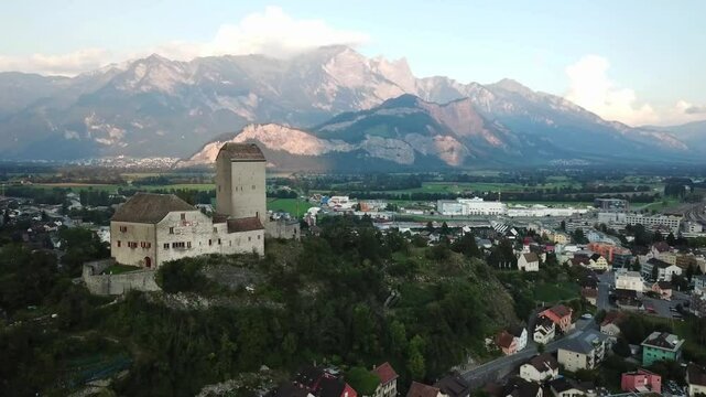 Aerial close up shot of Sargans castle towers over the town and the Rhine valley, with a breathtaking view of the swiss alps in the background, St. Gallen, Switzerland