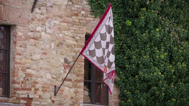 Bagno Vignoni flag Tuscany region Italy moving with wind next to historical building