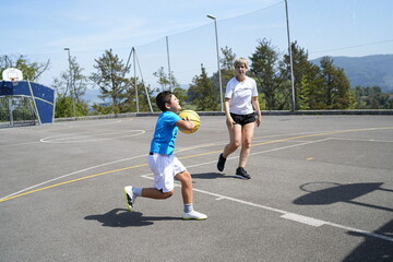 Obraz premium Mother and son playing basketball outdoors on a sunny day