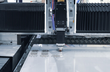 CNC fiber laser cutting machine cutting metal sheet with flying sparks. Industrial metalworking...